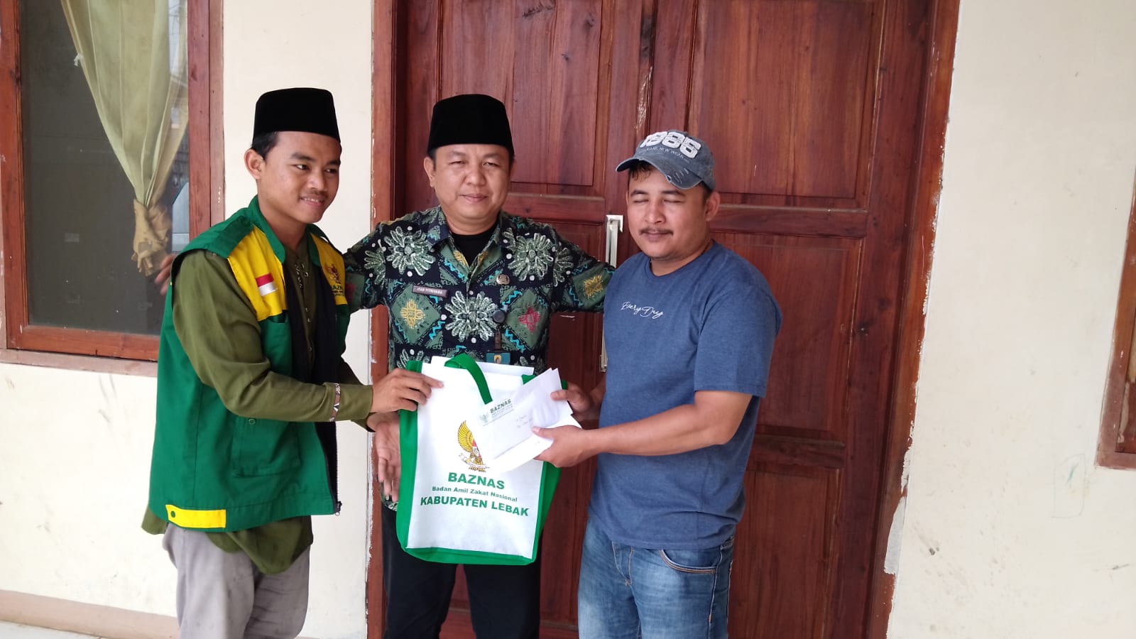 Foto: Petugas dari Baznas Kabupaten Lebak menyerahkan bantuan secara langsung kepada perwakilan keluarga korban longsor, yang diterima oleh anak dari pemilik rumah terdampak, di Kampung Cikadu, Desa Jagaraksa, Kecamatan Muncang.
