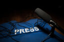 Media Journalism Global Daily News Content Concept. Blue journalist (press) vest in dark with backlight and fog. Media microphone on journalist vest. Selective focus