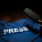 Media Journalism Global Daily News Content Concept. Blue journalist (press) vest in dark with backlight and fog. Media microphone on journalist vest. Selective focus